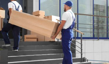 1565370691332_bigstock_male_movers_carrying_shelving_258427084